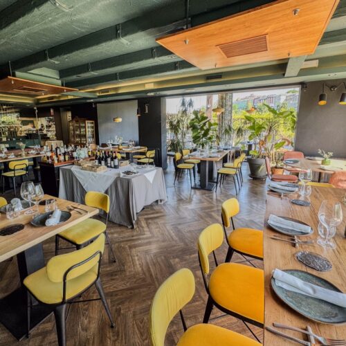 Comedor de Canedo Restaurante en Lugo con mesas de madera, sillas amarillas y grandes ventanales