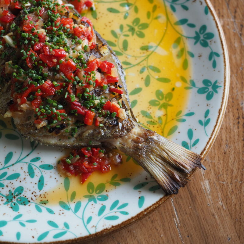Pescado salvaje a la brasa servido entero con vinagreta y cebollino
