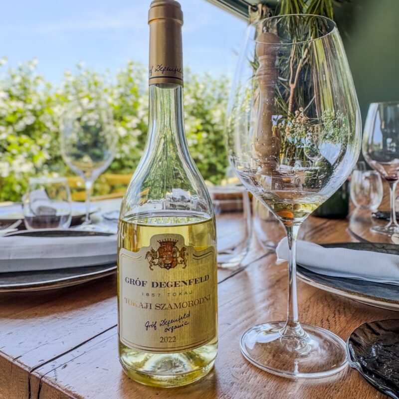 Botella de vino Tokaji junto a una copa en una mesa del comedor